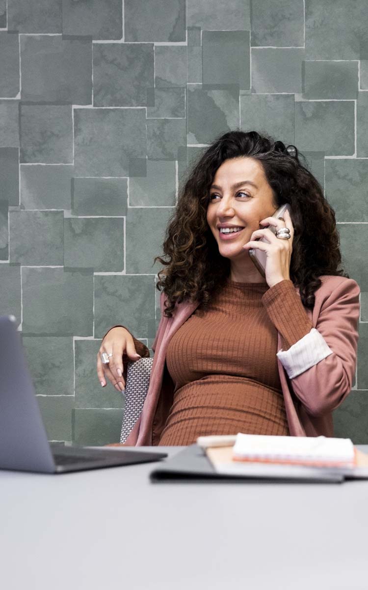 Hymyilevä nainen puhuu puhelimessa.